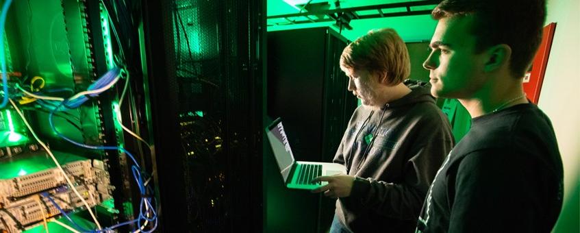 Two Information Technology and Networking students working in a server room.